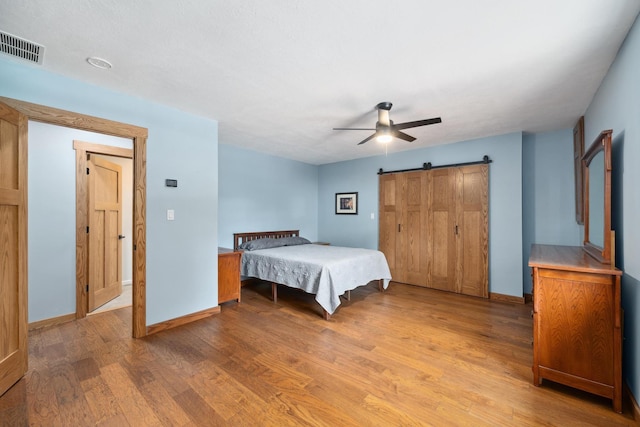 1209 Redbud Dr, Arlington, TX 76012 - bedroom featuring light wood-style floors, a barn door, baseboards, and a ceiling fan