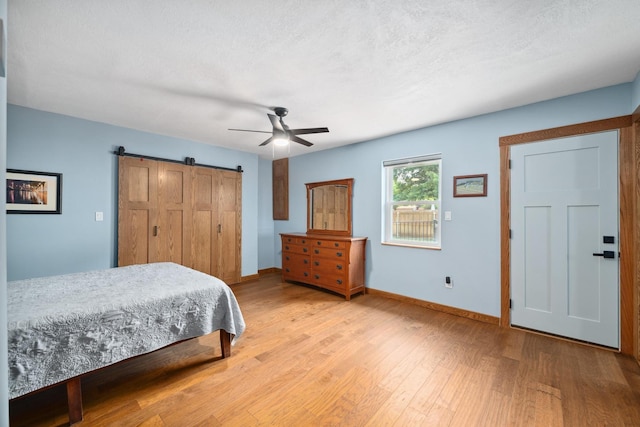 1209 Redbud Dr, Arlington, TX 76012 - bedroom with light wood-style floors, baseboards, a barn door, and ceiling fan