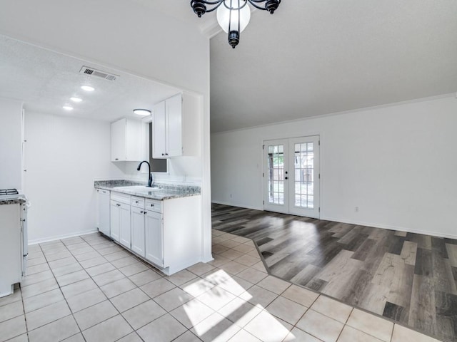 1429 Meadowcrest Dr, Plano, TX 75075 - kitchen with a sink, light tile patterned flooring, french doors, white cabinets, and ornamental molding