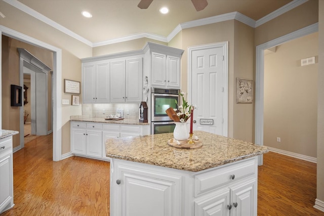 5505 Moorewood Dr, Arlington, TX 76017 - kitchen with double oven, light wood finished floors, ceiling fan, backsplash, and white cabinetry