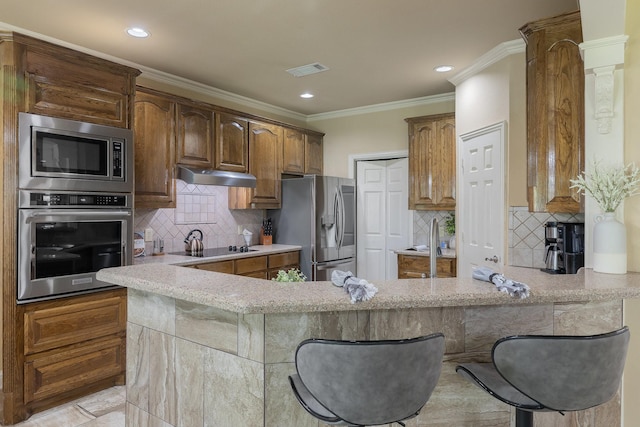 18 Oxford Way, Allen, TX 75002 - kitchen with appliances with stainless steel finishes, under cabinet range hood, a peninsula, backsplash, and ornamental molding