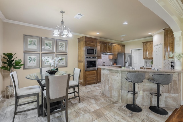 18 Oxford Way, Allen, TX 75002 - kitchen with appliances with stainless steel finishes, under cabinet range hood, arched walkways, crown molding, and backsplash