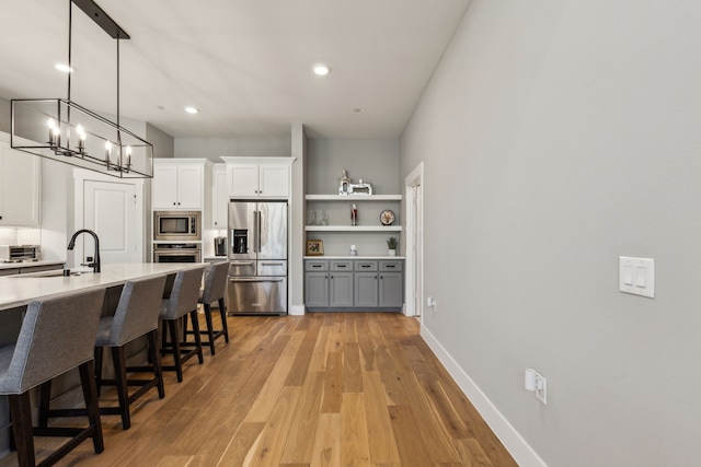 3900 Dalea Dr, Prosper, TX 75078 - kitchen featuring appliances with stainless steel finishes, light countertops, a kitchen breakfast bar, white cabinets, and hanging light fixtures
