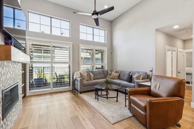 3900 Dalea Dr, Prosper, TX 75078 - living room featuring wood finished floors, a ceiling fan, a tiled fireplace, recessed lighting, and a high ceiling