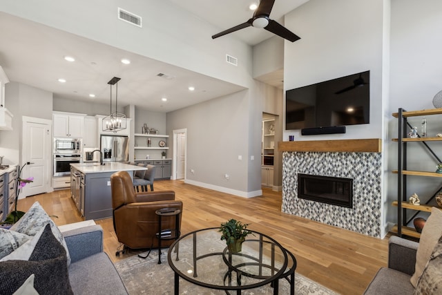 3900 Dalea Dr, Prosper, TX 75078 - living area with ceiling fan, light wood finished floors, a fireplace, built in shelves, and a towering ceiling