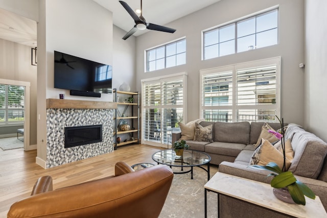3900 Dalea Dr, Prosper, TX 75078 - living room featuring a high ceiling, wood finished floors, ceiling fan, and a tile fireplace