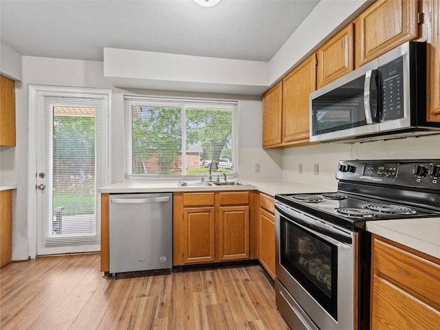 2036 Pearl Ln, Irving, TX 75060 - kitchen featuring appliances with stainless steel finishes, a sink, light countertops, and light wood finished floors