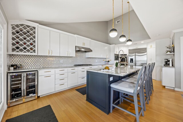 510 Columbia Dr, Rockwall, TX 75032 - kitchen with wine cooler, under cabinet range hood, built in appliances, white cabinets, and tasteful backsplash
