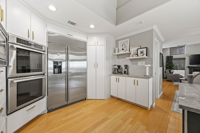 510 Columbia Dr, Rockwall, TX 75032 - kitchen featuring stainless steel appliances, ornamental molding, light wood-style flooring, white cabinets, and open shelves