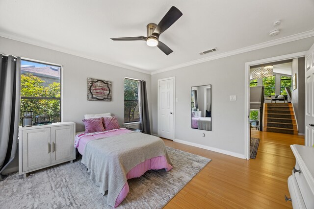 510 Columbia Dr, Rockwall, TX 75032 - bedroom with crown molding, light wood-style flooring, baseboards, a ceiling fan, and a chandelier