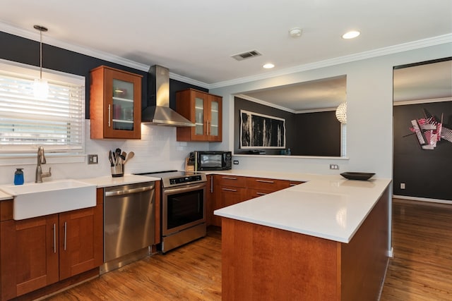 9914 Woodgrove Dr, Dallas, TX 75218 - kitchen featuring stainless steel appliances, wall chimney exhaust hood, a sink, brown cabinets, and wood finished floors