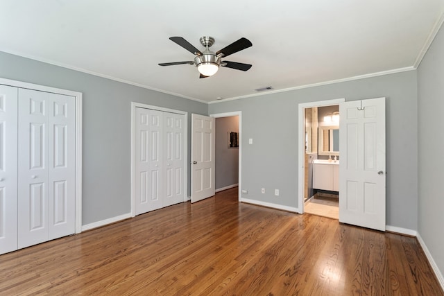 9914 Woodgrove Dr, Dallas, TX 75218 - unfurnished bedroom with two closets, wood finished floors, baseboards, crown molding, and ensuite bathroom