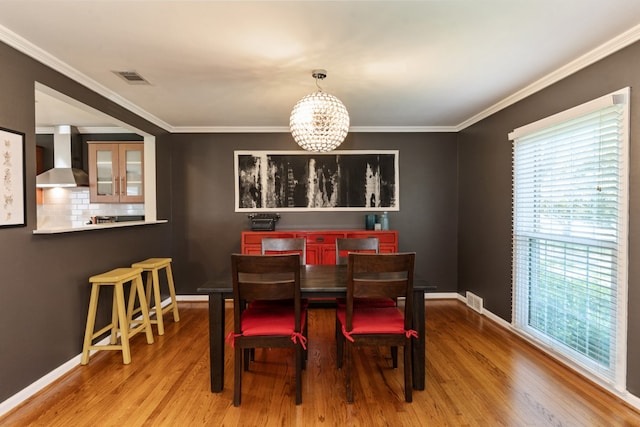 9914 Woodgrove Dr, Dallas, TX 75218 - dining room featuring healthy amount of natural light, wood finished floors, a chandelier, and crown molding
