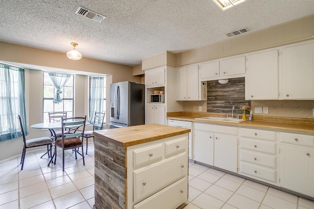 1312 Robyn Rd, Azle, TX 76020 - kitchen with stainless steel appliances, a sink, light tile patterned floors, butcher block counters, and white cabinetry