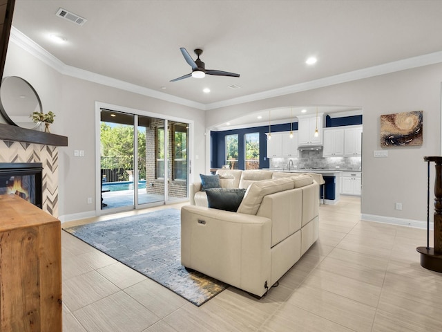 318 Arcadia Way, Rockwall, TX 75087 - living room featuring a ceiling fan, ornamental molding, a glass covered fireplace, recessed lighting, and baseboards