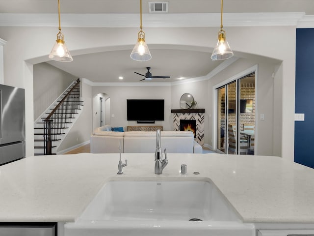 318 Arcadia Way, Rockwall, TX 75087 - kitchen with freestanding refrigerator, ceiling fan, a sink, a warm lit fireplace, and crown molding