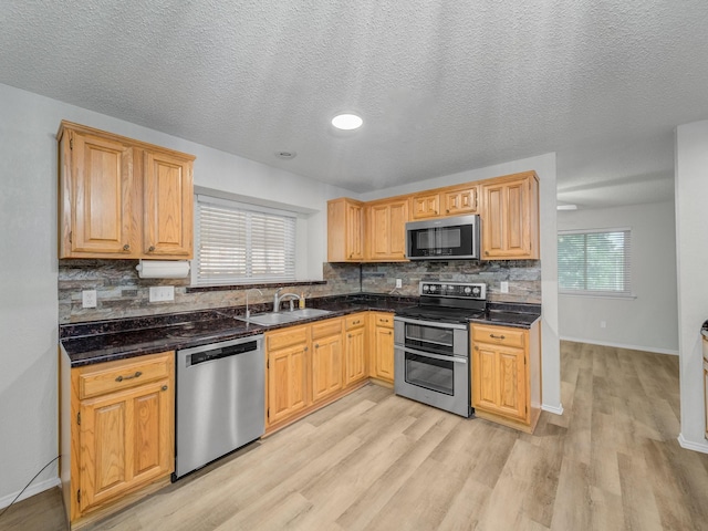 300 Lark Ln, Euless, TX 76039 - kitchen with stainless steel appliances, a sink, light wood-style flooring, backsplash, and baseboards