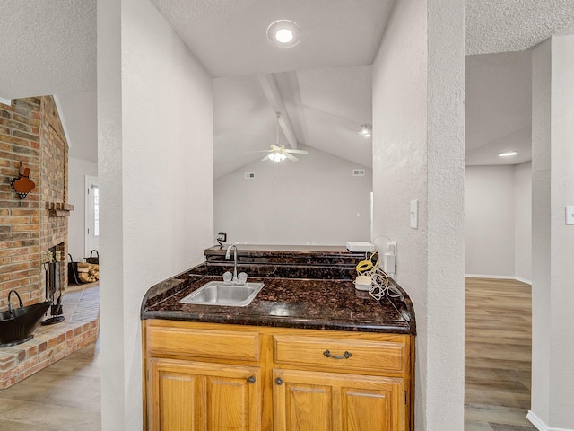 300 Lark Ln, Euless, TX 76039 - kitchen with a sink, dark stone countertops, a ceiling fan, light wood-type flooring, and baseboards
