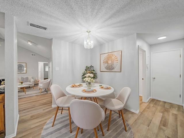 300 Lark Ln, Euless, TX 76039 - dining room with light wood-type flooring, a textured ceiling, a chandelier, lofted ceiling, and baseboards