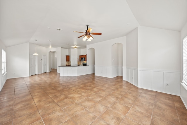 332 Butternut Dr, Fate, TX 75087 - unfurnished living room with arched walkways, vaulted ceiling, ceiling fan, plenty of natural light, and a wainscoted wall