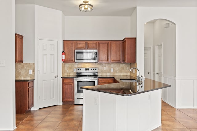 332 Butternut Dr, Fate, TX 75087 - kitchen with appliances with stainless steel finishes, a sink, light tile patterned floors, arched walkways, and a peninsula