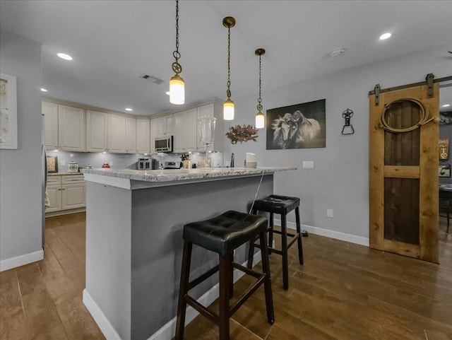 7409 Harbor Dr, Rowlett, TX 75088 - kitchen featuring dark wood-style floors, stainless steel microwave, baseboards, a kitchen bar, and recessed lighting