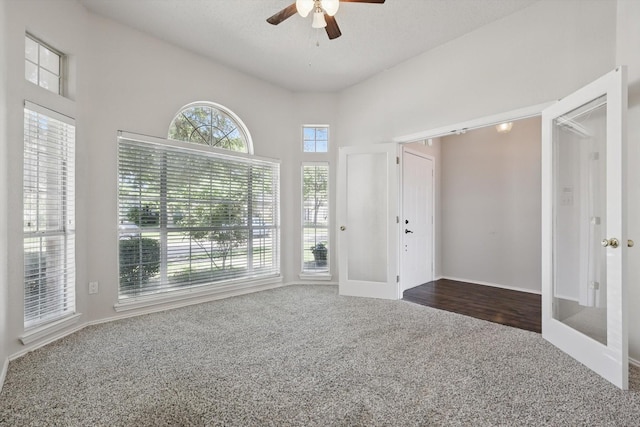 7100 Fox Dr, The Colony, TX 75056 - entrance foyer with dark colored carpet, a ceiling fan, french doors, a high ceiling, and baseboards