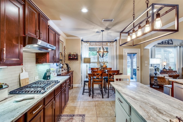 2801 Adams Dr, Melissa, TX 75454 - kitchen featuring under cabinet range hood, stainless steel gas stovetop, a chandelier, decorative backsplash, and light stone counters