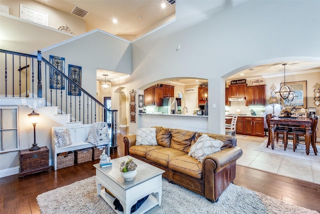 2801 Adams Dr, Melissa, TX 75454 - living room with light wood-style flooring, a high ceiling, stairway, arched walkways, and crown molding
