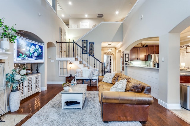 2801 Adams Dr, Melissa, TX 75454 - living room with arched walkways, stairway, wood finished floors, a high ceiling, and recessed lighting