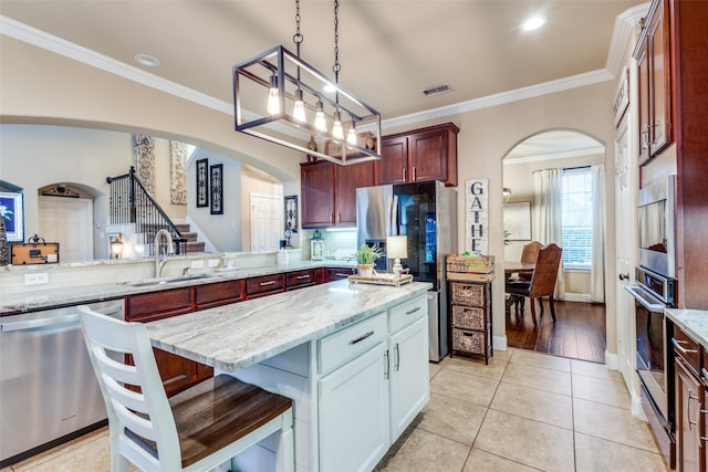 2801 Adams Dr, Melissa, TX 75454 - kitchen featuring stainless steel appliances, a sink, arched walkways, crown molding, and light stone countertops