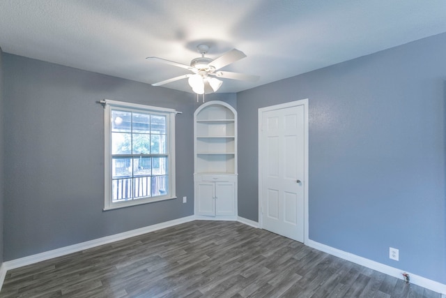 901 E Walnut St, Hillsboro, TX 76645 - empty room featuring dark wood finished floors, ceiling fan, baseboards, and built in shelves