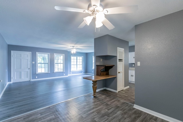 901 E Walnut St, Hillsboro, TX 76645 - unfurnished living room featuring a ceiling fan, baseboards, dark wood finished floors, and a textured wall
