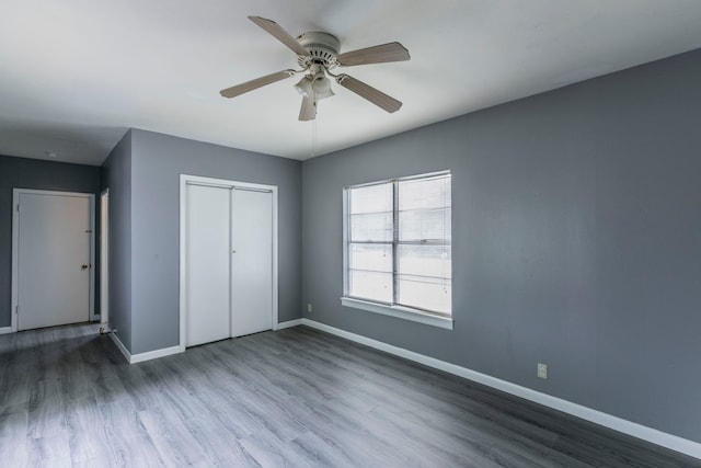 901 E Walnut St, Hillsboro, TX 76645 - unfurnished bedroom with baseboards, a closet, wood finished floors, and a ceiling fan