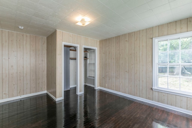 901 E Walnut St, Hillsboro, TX 76645 - empty room featuring hardwood / wood-style floors, wooden walls, plenty of natural light, and baseboards