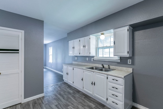 901 E Walnut St, Hillsboro, TX 76645 - kitchen with a sink, light countertops, white cabinets, dark wood finished floors, and a textured wall