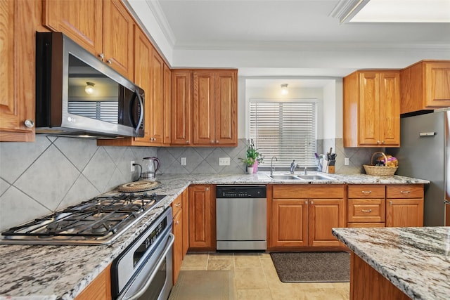 9829 Crawford Farms Dr, Fort Worth, TX 76244 - kitchen featuring appliances with stainless steel finishes, a sink, ornamental molding, light stone counters, and brown cabinetry