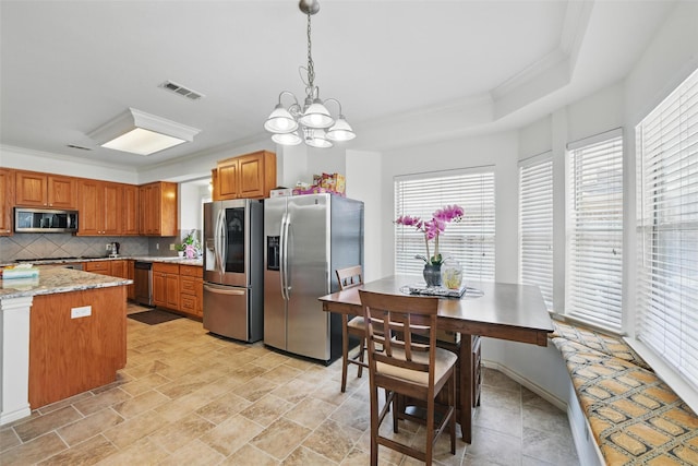 9829 Crawford Farms Dr, Fort Worth, TX 76244 - kitchen with appliances with stainless steel finishes, brown cabinetry, backsplash, a chandelier, and ornamental molding