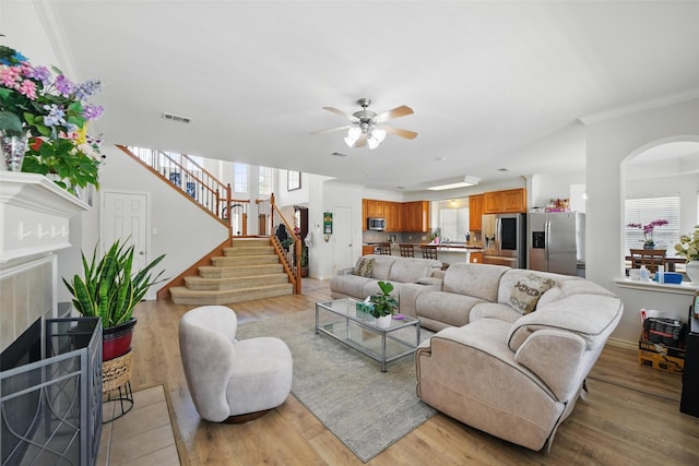 9829 Crawford Farms Dr, Fort Worth, TX 76244 - living area with ceiling fan, light wood-style floors, stairs, ornamental molding, and arched walkways