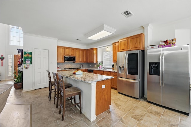 9829 Crawford Farms Dr, Fort Worth, TX 76244 - kitchen featuring stainless steel appliances, ornamental molding, a kitchen island, a kitchen breakfast bar, and light stone counters