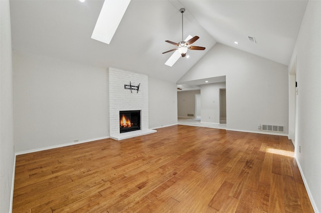 5518 Oak Branch Dr, Arlington, TX 76016 - unfurnished living room featuring high vaulted ceiling, a skylight, a ceiling fan, a brick fireplace, and light wood-type flooring