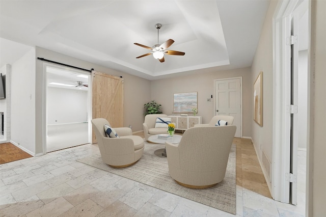 5518 Oak Branch Dr, Arlington, TX 76016 - living area with a tray ceiling, a ceiling fan, a barn door, and baseboards