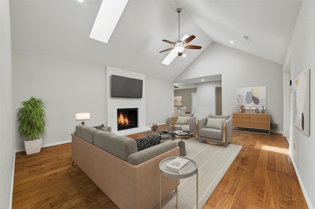 5518 Oak Branch Dr, Arlington, TX 76016 - living area featuring a skylight, high vaulted ceiling, a brick fireplace, a ceiling fan, and wood finished floors