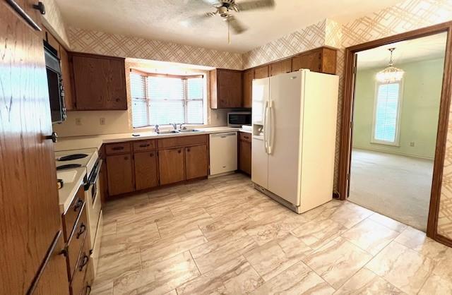 2621 Picadilly Ln, Denton, TX 76209 - kitchen featuring white appliances, wallpapered walls, a ceiling fan, light countertops, and plenty of natural light