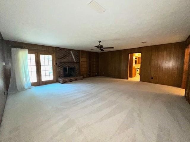 2621 Picadilly Ln, Denton, TX 76209 - unfurnished living room with light colored carpet, wood walls, ceiling fan, and a fireplace