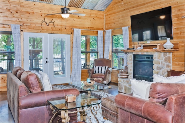 520 County Road 1743, Chico, TX 76431 - living room with wooden walls, a ceiling fan, a fireplace, high vaulted ceiling, and french doors