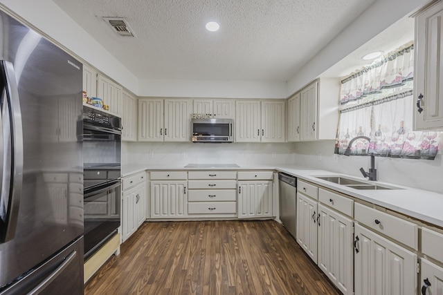 1808 Tameria Dr, Irving, TX 75060 - kitchen featuring appliances with stainless steel finishes, a sink, a textured ceiling, light countertops, and dark wood-type flooring
