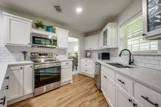2208 Turtle Creek Dr, Sherman, TX 75092 - kitchen with stainless steel appliances, a sink, decorative backsplash, white cabinetry, and glass insert cabinets
