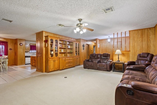109 Hilltop St, Riesel, TX 76682 - living area featuring wood walls, light carpet, a ceiling fan, a textured ceiling, and light tile patterned floors