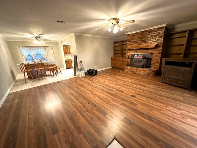 225 Jp Cave Rd, Sherman, TX 75090 - unfurnished living room with a ceiling fan, a wood stove, baseboards, ornamental molding, and wood finished floors